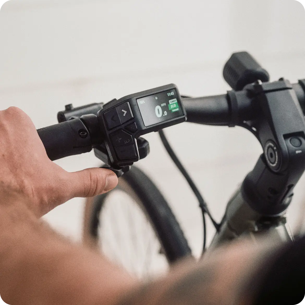 A hand grips the handlebar of the Velotric Tempo by Velotric, highlighting its control display with speed, battery, and settings—ideal for city rides on this lightweight electric bike.