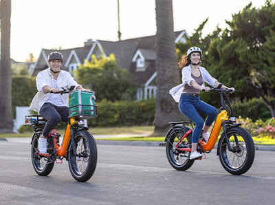 Two people riding HeyBike - Horizon electric bikes with fat tires on a suburban street, smiling, with one carrying a green delivery box on the rear rack.