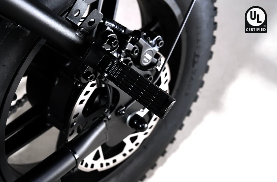 Close-up of a Rictor Glyde fat tire electric bike rear wheel featuring a mechanical disc brake, a passenger foot peg, and a UL Certified logo.