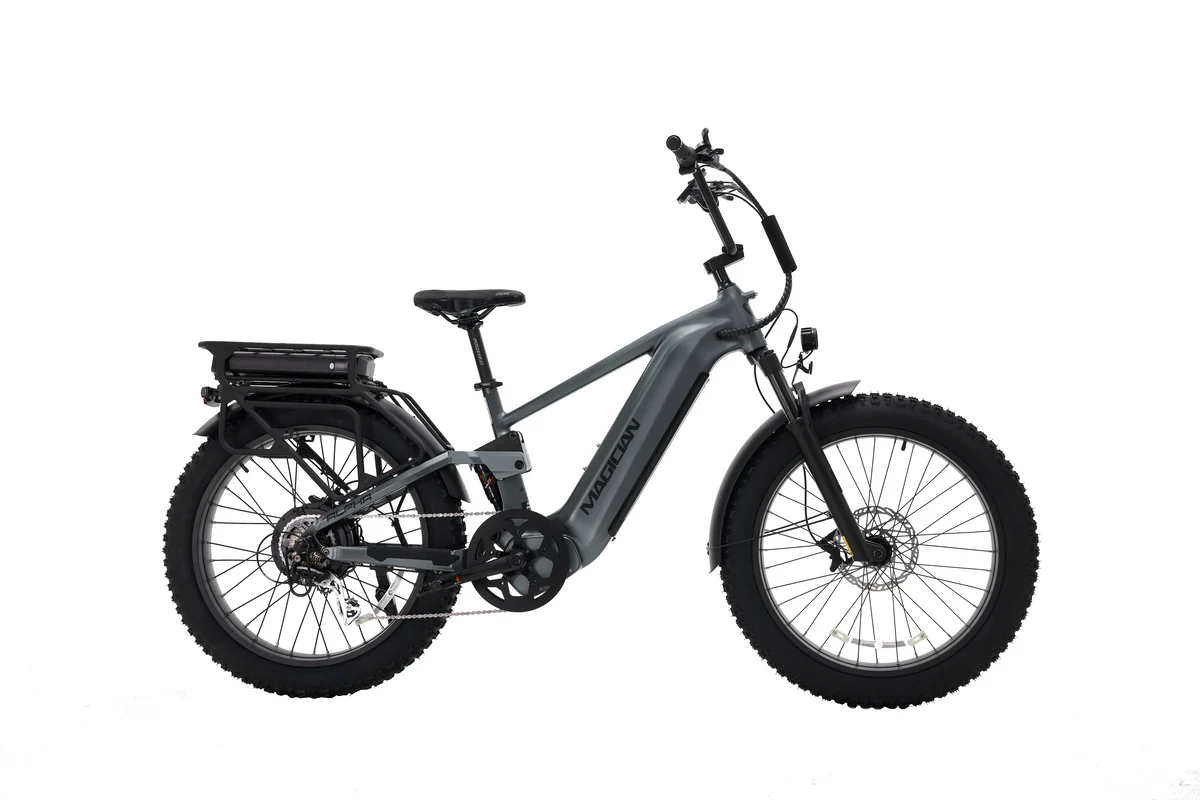 The Magician Alpha by Magician, a gray high-power electric bike with fat tires, front suspension, rear cargo rack, and disc brakes, is shown in profile on a white background.