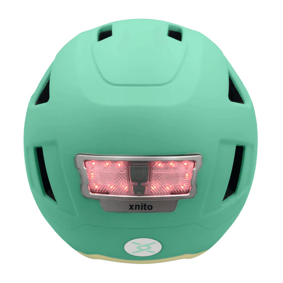 The Helmet XNITO - Old School - Mint, by XNITO, is a mint green e-bike helmet featuring black vents and an aerodynamic design. It includes a red LED light at the back for enhanced visibility and safety on every ride.