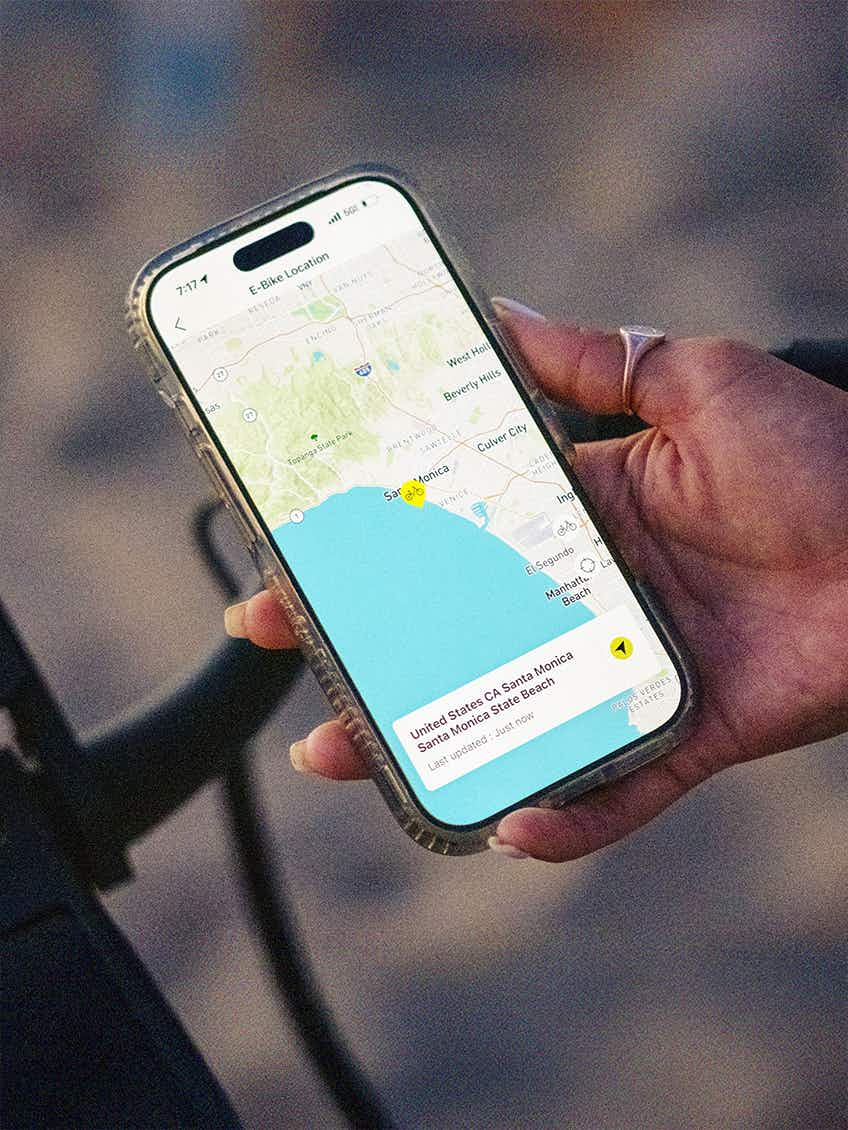 A hand holds a smartphone showing a map of Santa Monica with a location marked—ideal for planning your next beach ride on the Aventon Pace 5 REC Step-Through from Aventon.