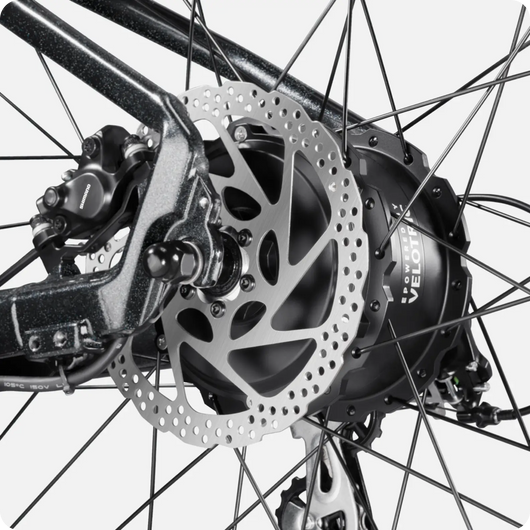 Close-up view of a Velotric Summit 1 rear hub and disc brake system, showing intricate details of the spokes and rotor.