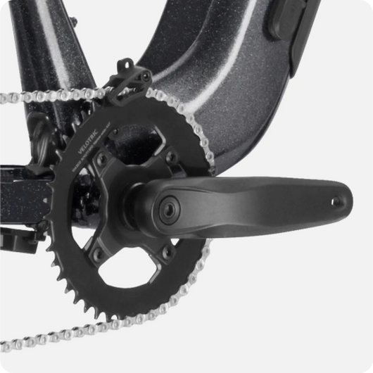 Close-up of a Velotric Summit 1 bicycle crankset and chainring with a partial view of a black chain guard.