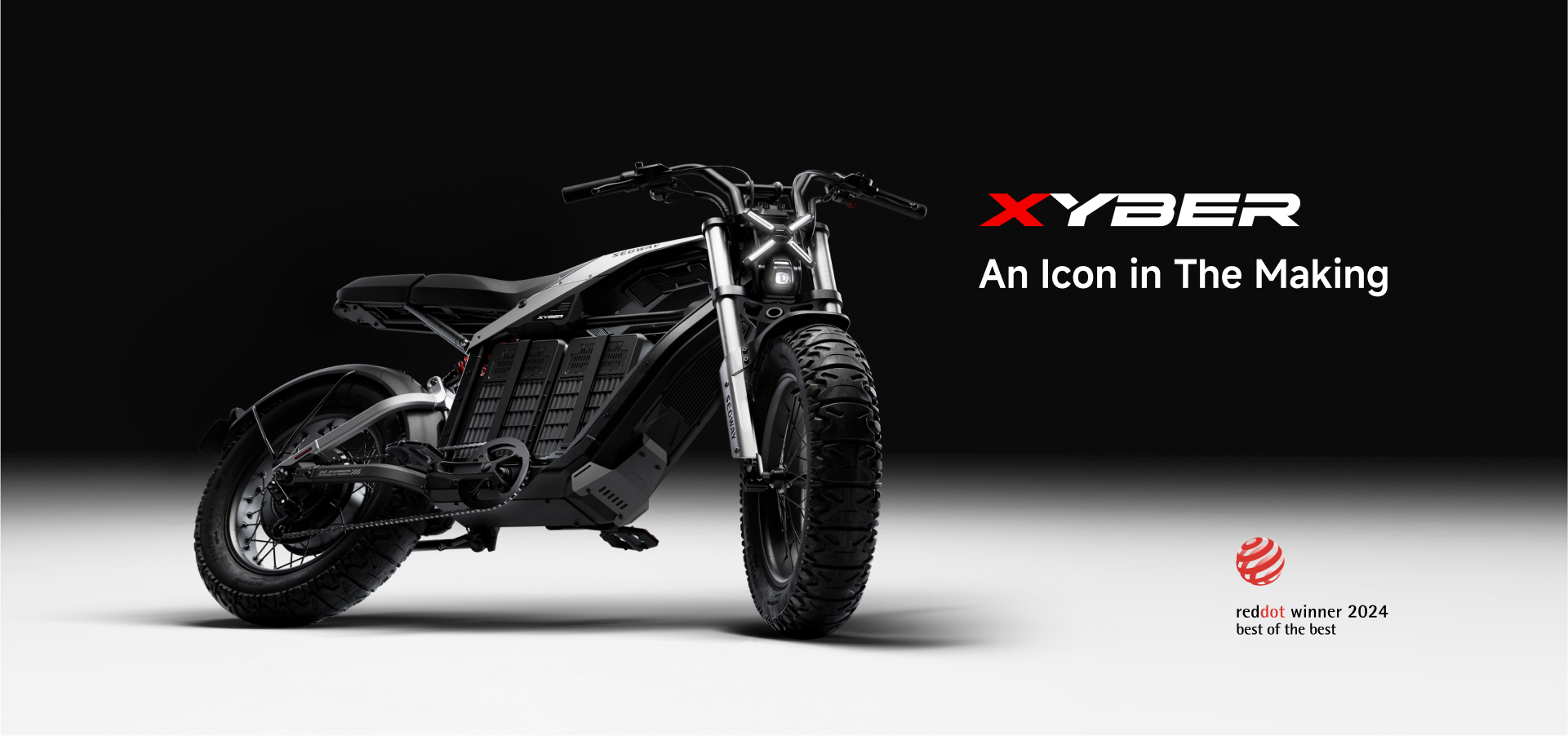 A sleek black Segway - Xyber electric bike is displayed on a white and black gradient backdrop. The text reads "Segway Xyber, An Icon in The Making" alongside the "RedDot Winner 2024 Best of the Best" badge.