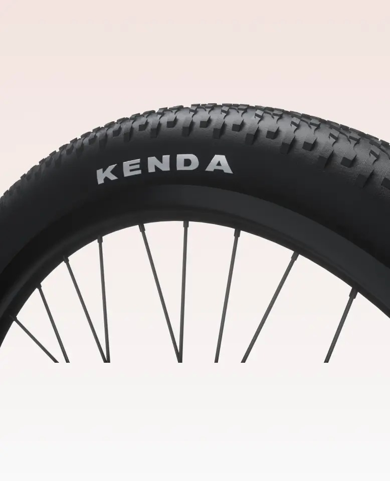 A close-up of a black bicycle tire with "KENDA" in white, plus rim and spokes detail—an ideal fit for the Velotric Discover 3 commuter eBike—set against a light background.
