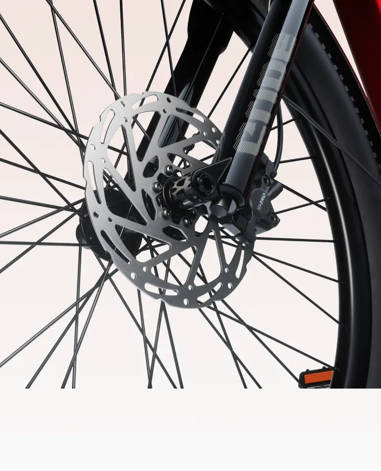 Close-up of the Velotric Discover 3 by Velotric, highlighting its front wheel with disc brake and multiple spokes against a light background.