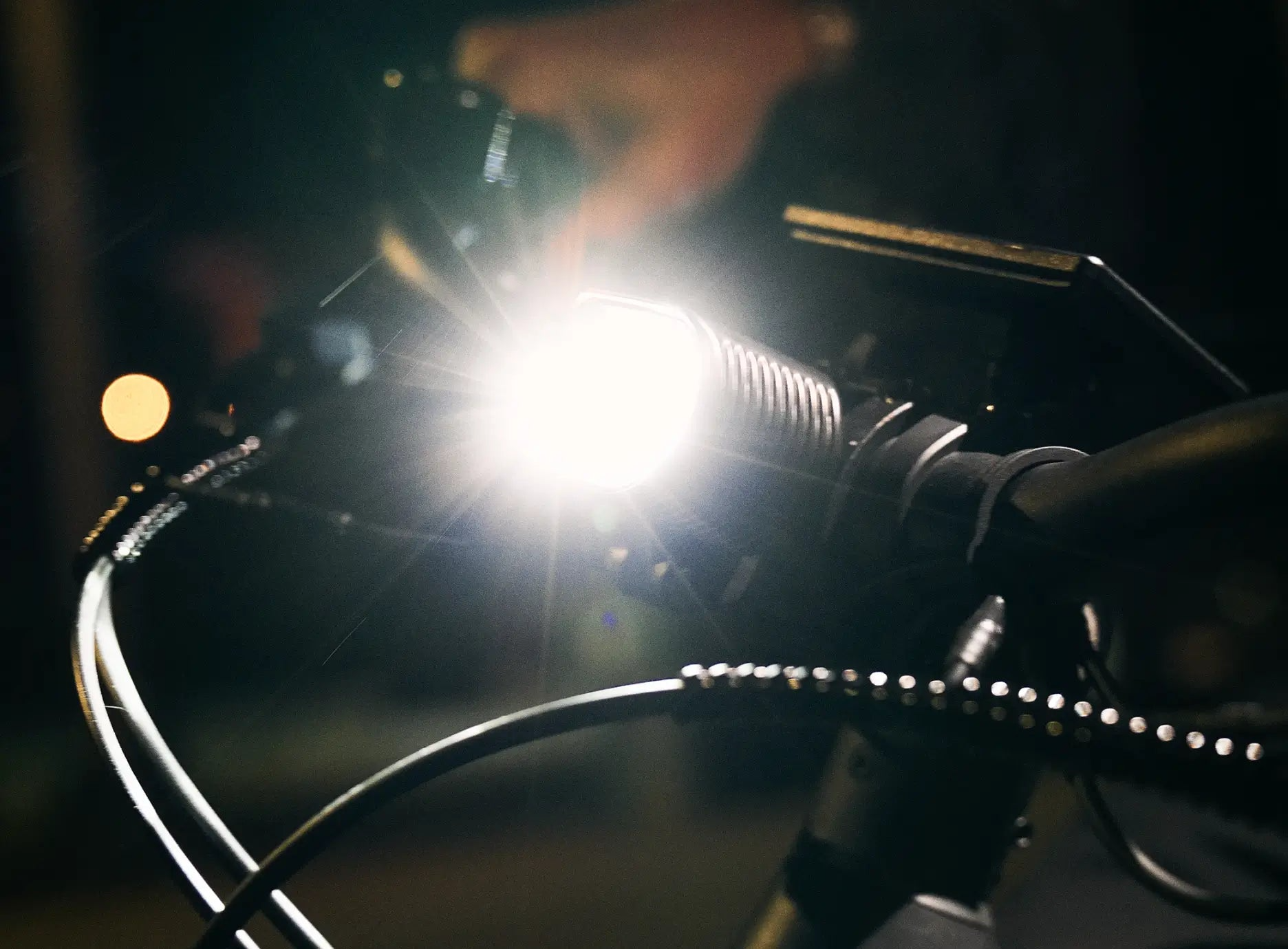 Close-up of the Velotric Discover M handlebar at night—its bright headlight, a highlight of Velotric comfort commuter eBike features, lights up the surroundings and ensures safer nighttime rides.