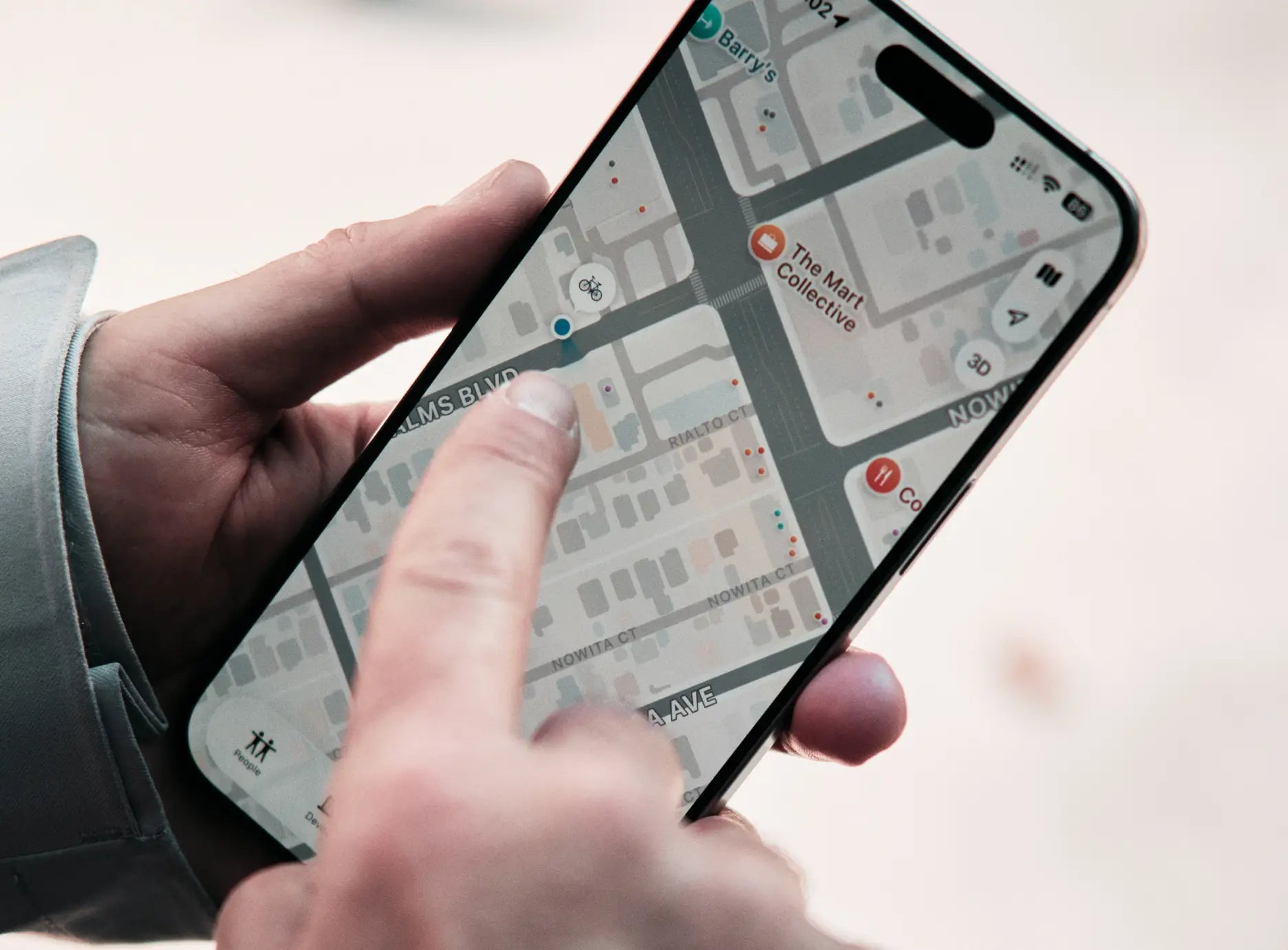A person uses their finger to navigate a map app on a smartphone, searching for locations or directions—possibly planning their next ride on the Velotric Discover M comfort commuter eBike from Velotric.